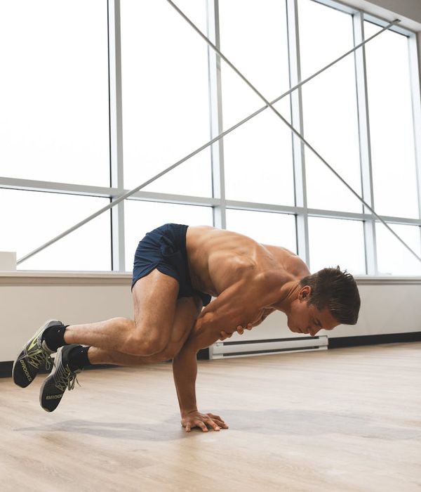 Man performing a dynamic strength exercise in a bright studio.